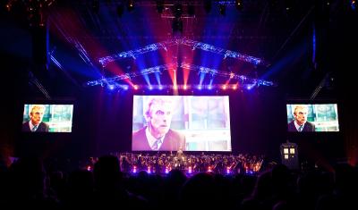 The Doctor Peter Capaldi on the screen while Ben Foster conducts the BBC National Orchestra of Wales and the BBC National Chorus of Wales. (Credit: House PR)